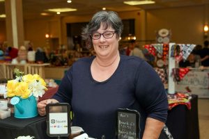 Owner of Freda Jane's at a craft show behind the table