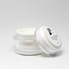 jar of face moisturizer with the lid leaning on jar with white background
